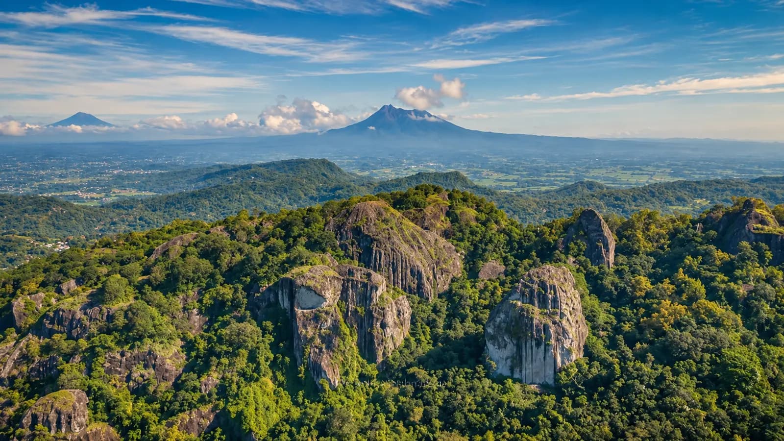 Large volcanic rock formations and green hills at Nglanggeran Ancient Volcano in Gunungkidul