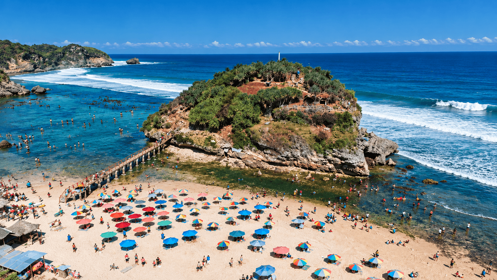A panoramic view of Drini Beach in Gunungkidul, Indonesia, featuring white sand, rocky islets, fishing boats, and the Indian Ocean.